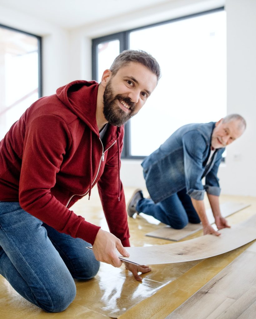 a-mature-man-with-his-senior-father-laying-vinyl-flooring-a-new-home-concept-.jpg